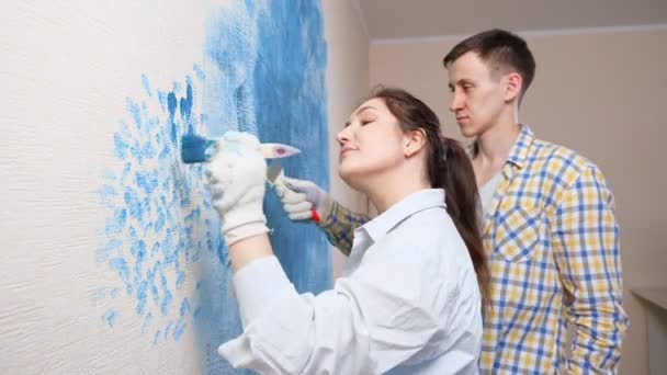 Jóvenes diseñadores dama y hombre en guantes blancos dibujar en la pared — Vídeos de Stock