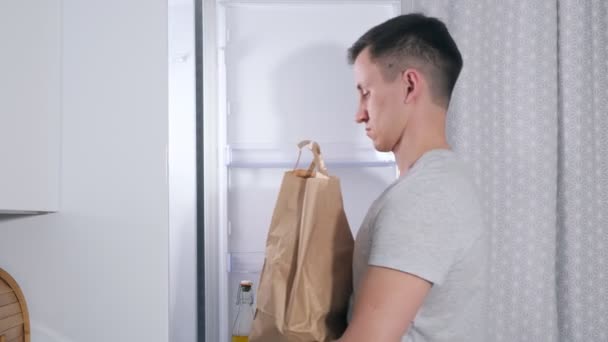 年轻人把不同的食品放进大冰箱里 — 图库视频影像