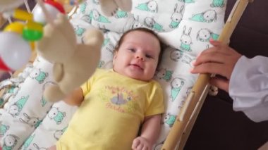 Genç anne sallanıyor beşikte beşikte, vücut kıyafetli kız bebekle