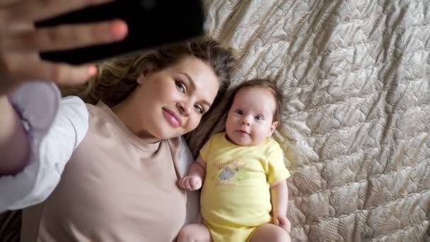 Veselá mladá matka s kudrnatými vlasy fotí dceru — Stock video