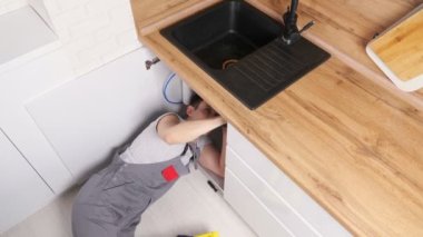 Gri üniformalı tesisatçı atık kapanı tamir eden boruları söktü