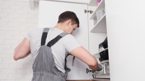 Young man in grey jumpsuit installs door twisting screws — Stock Video