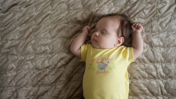 Baby flicka bär gula kläder vaknar på föräldrar säng — Stockvideo