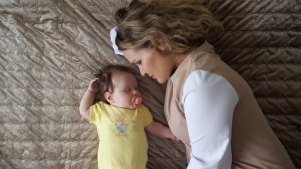 Cuidar jovem mãe encontra-se na cama grande perto de bebê menina — Vídeo de Stock