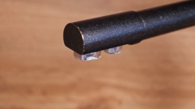 Siyah musluktan bej arkaplana su damlaları düşer