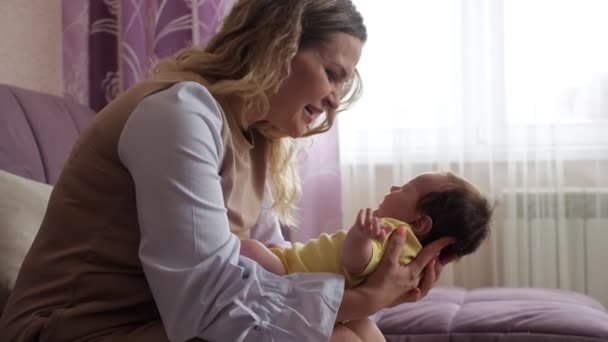 Jovem loira mãe acalma chorando bebê menina no sofá — Vídeo de Stock