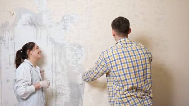 Kareli tişörtlü adam eski duvar kağıtlarını çıkarıyor. — Stok video