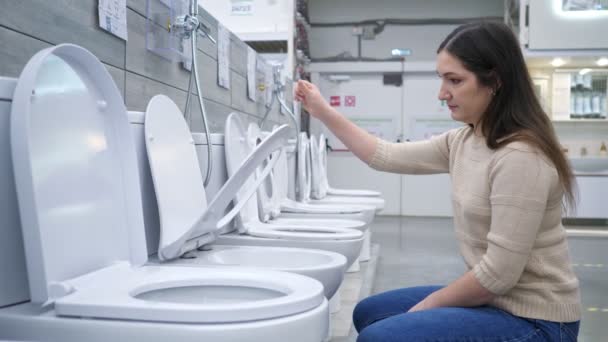Woman chooses toilet bowl with seat lift — Stock Video