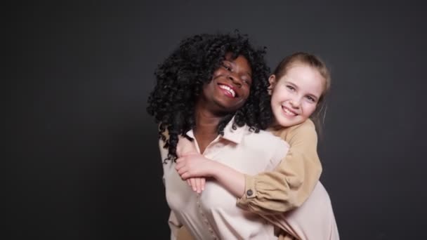 Afro-Amerikaanse dame met krullend haar houdt vrolijk meisje op de rug — Stockvideo