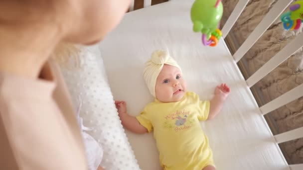 Jovem mãe fica perto bassinet e assiste bebê filha — Vídeo de Stock