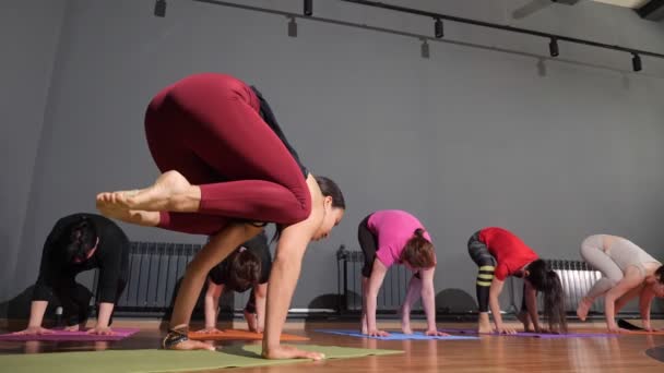 Woman yoga trainer showing hand balance with bent legs in group workout — Stok video