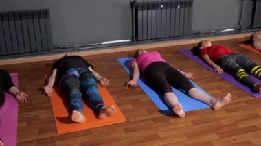 Group of workout classes relaxes after yoga exercises