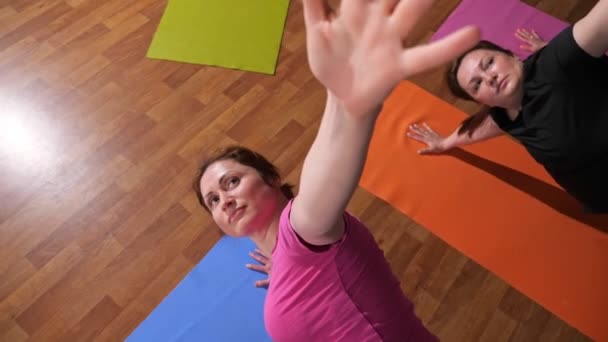 Young women in t-shirts practice yoga exercises on mats — Stok video