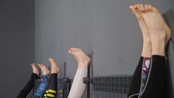 Yoga clasă doamnă practicieni se apleacă picioare pe perete gri — Videoclip de stoc