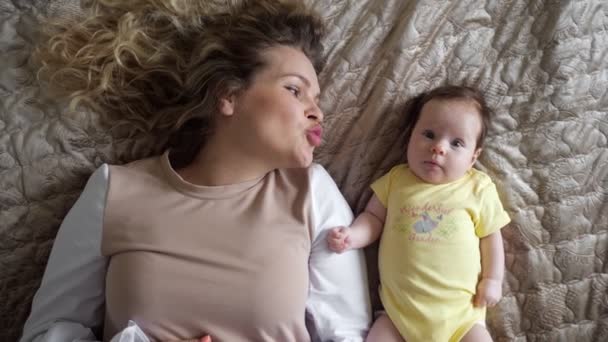 Joyful young mother with curly hair plays with baby daughter — Stock Video