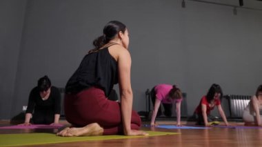Yoga koçu esmer, el ele tutuşarak egzersiz yapıyor.