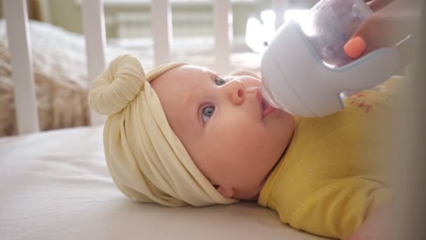 Primo piano di una bambina in una culla che beve acqua da una tazza di sippy — Video Stock