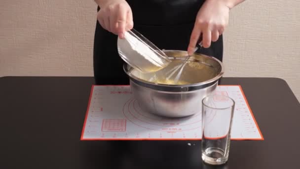 Unerkennbare Frau gießt Mehl in geschlagene Eier und mischt mit Schneebesen — Stockvideo