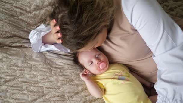 Liefdevolle jonge moeder ligt in de buurt van slapende kleine meisje — Stockvideo