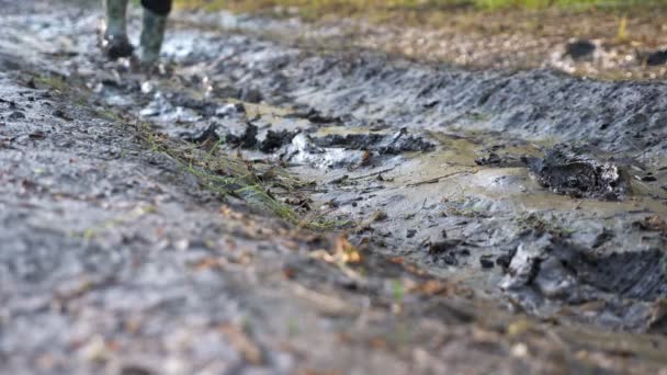 認識できない人がゴム製のブーツで泥の中を歩く — ストック動画
