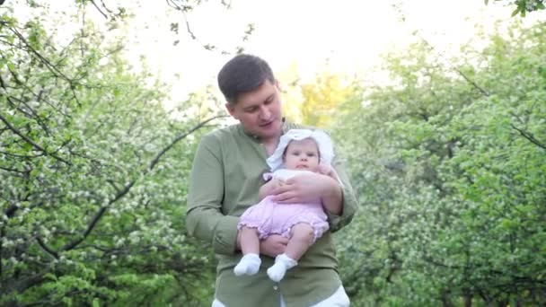 Sorrindo pai em camisa verde mantém bebê filha nos braços — Vídeo de Stock