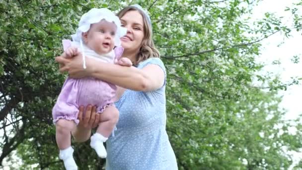 Young woman with loose fair hair rocks in arms baby girl — Stock Video