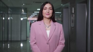 Mor ceketli esmer iş kadını koridorda poz veriyor.
