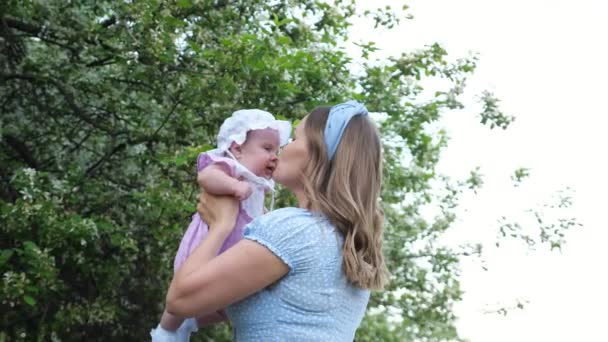 Vreugdevolle blonde moeder gooit grappig baby meisje en kussen kind — Stockvideo