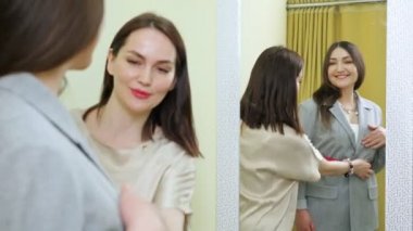 Satış asistanı, yeni gri ceketli kadına provada yardım ediyor.