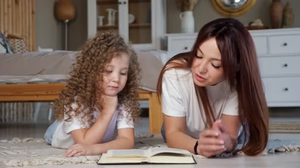 Brunetka matka czyta książki do małej dziewczynki z kręconymi włosami — Wideo stockowe