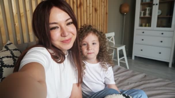 Jonge vrouw brunette poses voor camera en kussen dochter — Stockvideo
