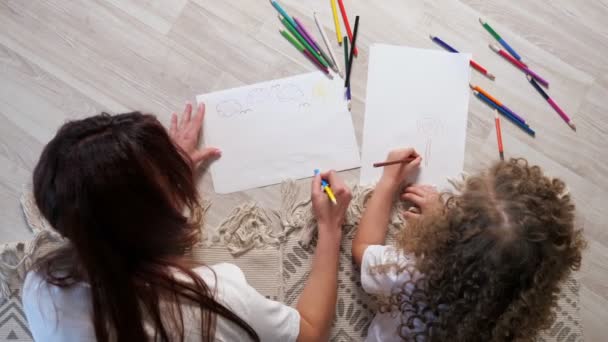 Brünette Mutter hilft kleinem Mädchen, Bild auf Papier zu zeichnen — Stockvideo