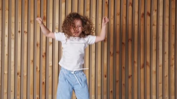 Předškolní dívka s dlouhými volné kudrnaté vlasy vyskočí s úsměvem — Stock video