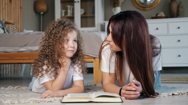 Sorrindo mãe lê conto de fadas para a filha pré-escolar no chão — Vídeo de Stock