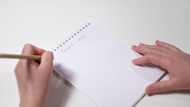 Κοντινό πλάνο των γυναικείων χεριών γράφοντας με το αριστερό χέρι τους στόχους για το 2022 — Αρχείο Βίντεο