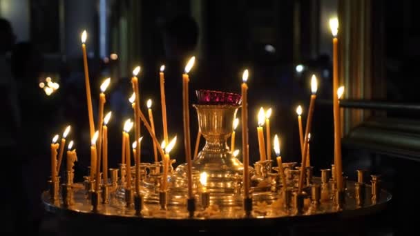 Velas de cera longa em um estande de ouro em uma igreja cristã — Vídeo de Stock