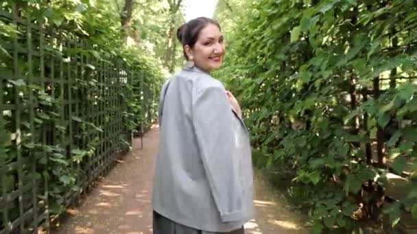 Genç bir kadın bahçede yürüyor ve gülümsüyor. — Stok video