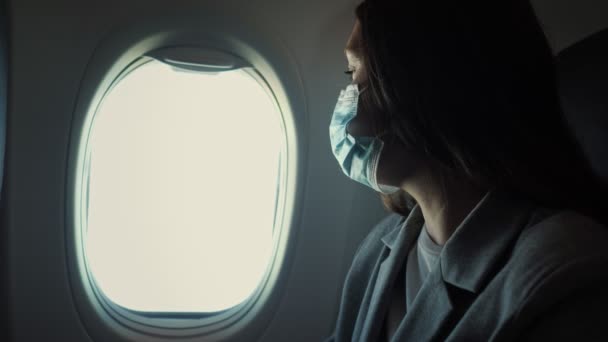 Femme dans un masque médical assis à la fenêtre d'un avion — Video