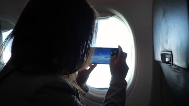 Tanımlanamayan bir kadın telefondaki uçak penceresinden manzarayı fotoğraflıyor.