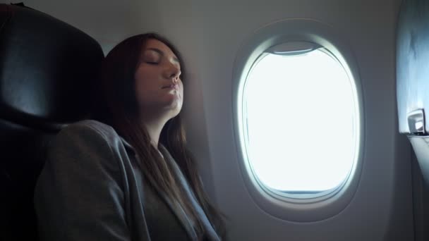 Brünette Frau schläft, während sie in einer unbequemen Position im Flugzeug sitzt — Stockvideo
