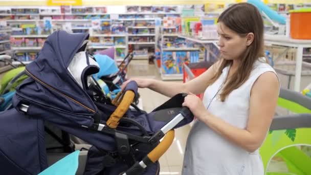 Vacker blivande mor väljer en barnvagn i en babyaffär — Stockvideo