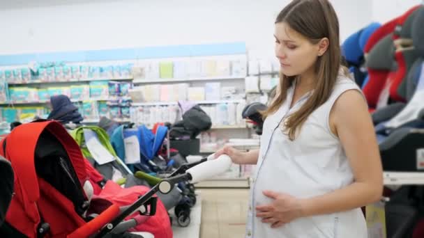妊婦は赤ん坊店でベビーカーを選ぶ — ストック動画