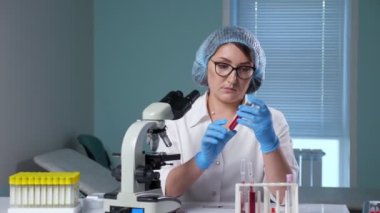 Gözlüklü doktor test tüpündeki sıvıya bakar.