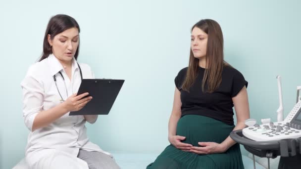 Gynécologue avec presse-papiers examine dame enceinte au bureau — Video