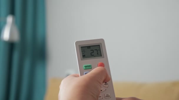 Primer plano de una mano que regula un aire acondicionado con un mando a distancia — Vídeos de Stock