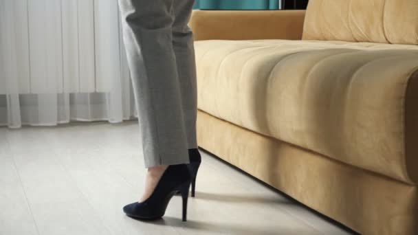 Αγνώριστη γυναίκα κάθεται στον καναπέ και βγάζει ψηλά τακούνια παπούτσια — Αρχείο Βίντεο
