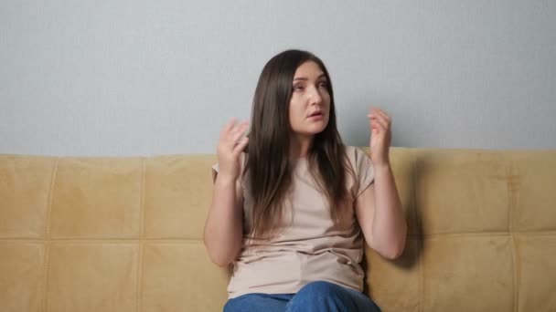 Žena si zakrývá uši a nadává na hluk sousedů, když sedí na gauči — Stock video