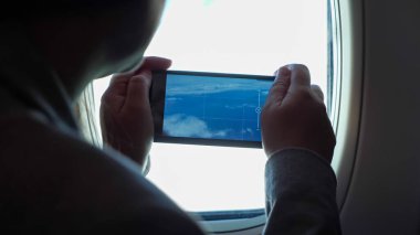 Tanımlanamayan bir kadın telefondaki lombozdan güzel bulutların videosunu çekiyor.