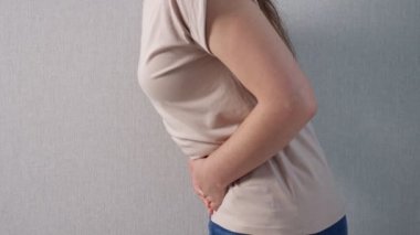 Karın ağrısı olan tanınmayan bir kadın, yandan bakıyor.