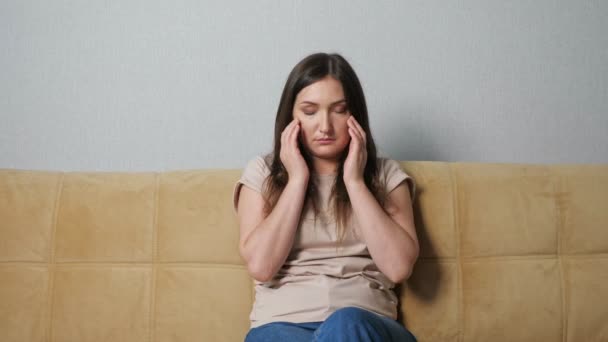 Jeune femme souffrant de maux de tête alors qu'elle était assise sur le canapé — Video